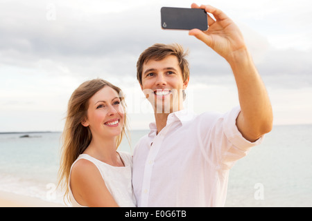 Happy young couple prenant une sur la plage selfies au coucher du soleil Banque D'Images