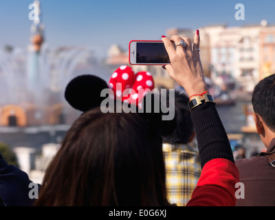 Femme à prendre des photos avec l'iPhone d'un show à Tokyo Disneysea parc à thème. Le Japon. Banque D'Images