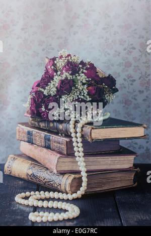 Un bouquet de roses séchées sur un tas de vieux livres Banque D'Images