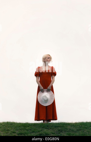 Une femme dans une robe rouge avec un chapeau blanc Banque D'Images