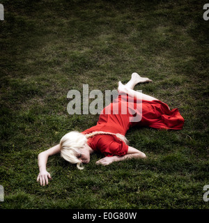Une femme en robe rouge est allongé dans l'herbe Banque D'Images
