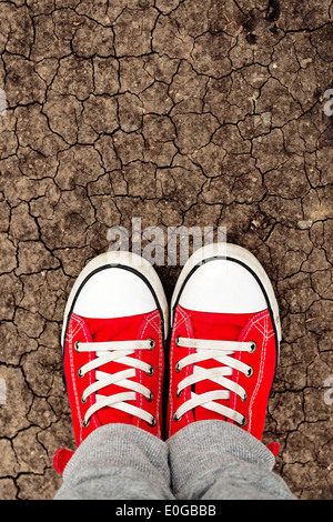 Garçon en rouge sneakers debout sur le terrain, d'en haut. Grandir avec toute la vie devant concept. La première étape. Banque D'Images