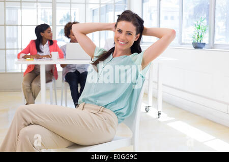 Businesswoman relaxing avec des collègues derrière elle Banque D'Images