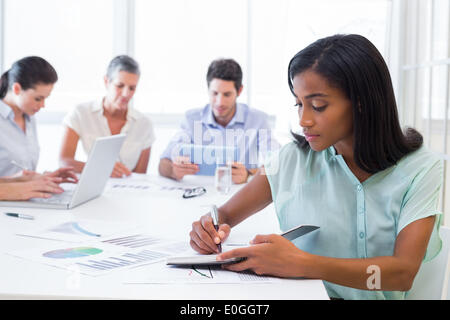 Casual businesswoman taking notes during meeting Banque D'Images