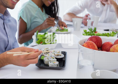 Les personnes bénéficiant d'affaires sushi et salade pour le déjeuner Banque D'Images