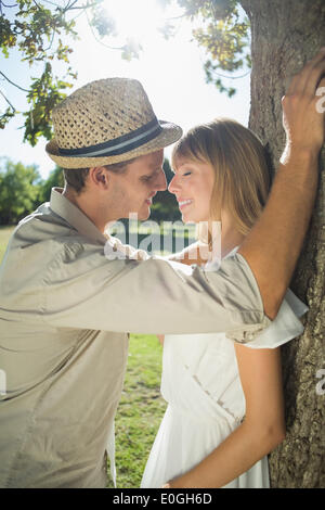 Cute couple leaning against tree dans le parc Banque D'Images