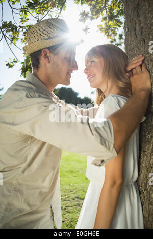 Cute couple leaning against tree dans le parc Banque D'Images