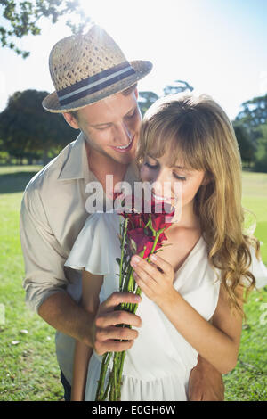 Attractive blonde smeling partenaire debout avec roses Banque D'Images