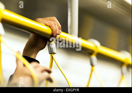 La main d'un holding de banlieue sur une rampe sur la foule London Underground tube train. Banque D'Images