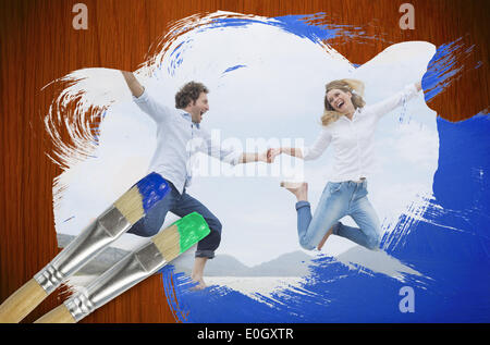 Image composite du couple jumping on the beach Banque D'Images