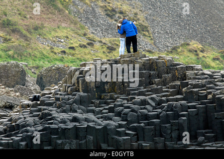 Couple debout sur des pierres de basalte à la Giant's Causeway, County Antrim, Northern Ireland, UK, Site du patrimoine mondial de l'UNESCO. Banque D'Images