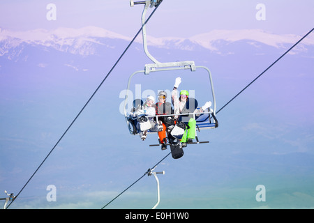 Trois surfeurs assis sur ropeway en montagne Banque D'Images