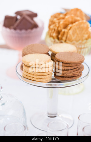 Libre de quatre piles de biscuit sec sur le verre au service de support avec morceaux de chocolat et les cookies dans des bols de gaufres en arrière-plan Banque D'Images