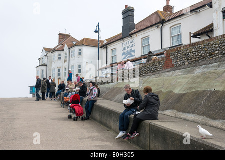 Les gens de manger du poisson et frites et assis sur un mur sur la promenade à Sheringham Norfolk UK Banque D'Images