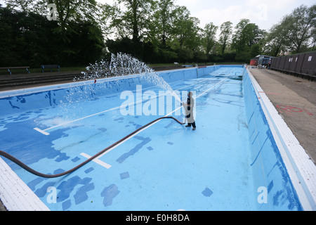 Un homme le remplissage d'une piscine extérieure avec un tuyau flexible Banque D'Images