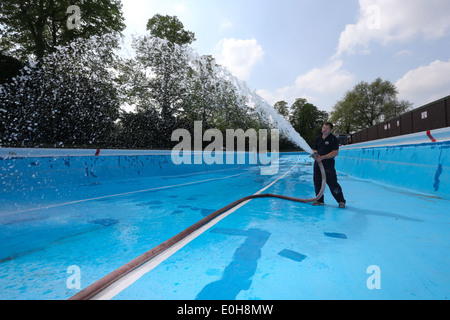 Un homme le remplissage d'une piscine extérieure avec un tuyau flexible Banque D'Images