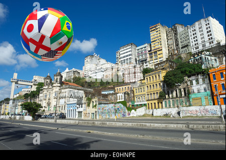 International football ballon de soccer volant dans le ciel au-dessus de Salvador de Bahia Brésil city skyline Banque D'Images