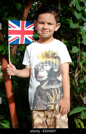 Petit garçon portant un singe punk union jack t shirt tenant un drapeau Union Jack à son domicile dans un village rural de l'Indonésie java Banque D'Images