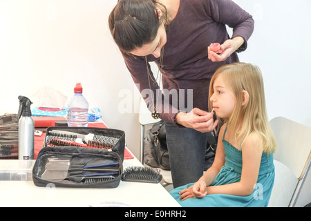 L'artiste de maquillage maquillage s'applique à un jeune modèle féminin lors d'une pousse de mode Banque D'Images