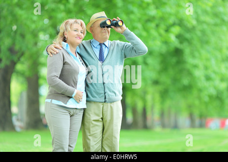 Senior couple looking through binoculars outdoors Banque D'Images