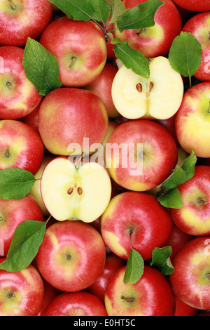 Collection de pommes rouges avec des feuilles formant un arrière-plan Banque D'Images