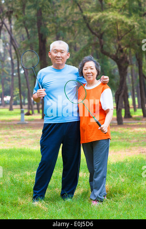 Smiling senior couple holding badminton racket dans le parc Banque D'Images