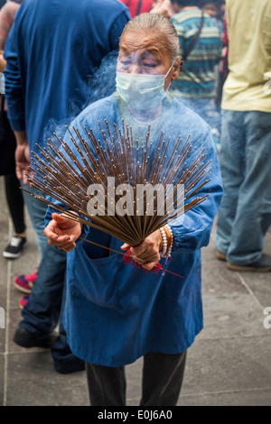 Senior woman holding d'encens à Hsing Tian Kong à Taiwan Banque D'Images