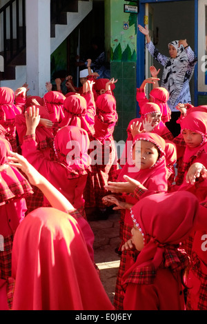 Les enfants de l'école primaire dans l'uniforme rouge vif s'aligner dans la cour de l'école avant d'enseignements Banque D'Images