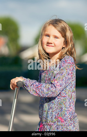 Petite fille monter le scooter dans le parc Banque D'Images