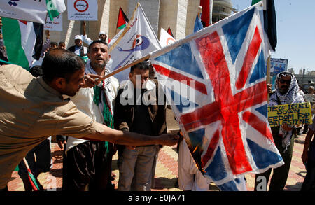 Rafah, la Palestine. 14 mai, 2014. Un palestiniens brûlent des répliques des drapeaux israéliens et britanniques au cours d'un rassemblement d'avance sur le 66e anniversaire de la Nakba, à Rafah dans le sud de la bande de Gaza le 14 mai 2014. Les Palestiniens ne marque "Nakba" (catastrophe) le 15 mai pour commémorer l'expulsion ou la fuite de quelque 700 000 Palestiniens de leurs maisons dans la guerre qui a mené à la fondation d'Israël en 1948.Photo : Abed Rahim Khatib/Pacific Press/Alamy Live News Banque D'Images