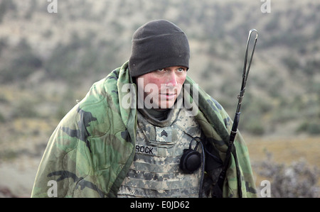 Le sergent de l'armée américaine. Nathan Schrock, de Arthur, Ill., essaie de garder au chaud après le réveil sur un matin froid dans les montagnes près de sa Banque D'Images