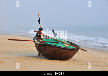 Pêcheur tirant son coracle également appelé 'panier' ou 'bateau' chai thung, tissé à partir de bambou, de la plage de Cua Dai, près de Hoi An, Vietnam, Southeast Asia Banque D'Images
