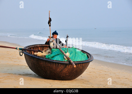 Pêcheur tirant son coracle également appelé 'panier' ou 'bateau' chai thung, tissé à partir de bambou, de la plage de Cua Dai, près de Hoi An, Vietnam, Southeast Asia Banque D'Images