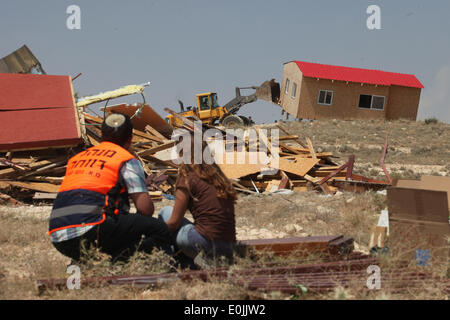 (140515) -- JÉRUSALEM, 15 mai 2014 (Xinhua) -- Un colon israélien (R) La montre alors qu'un bulldozer de l'armée israélienne démolit une construction illégales dans le règlement des Maale-Rechavam au nord d'Hébron, le 14 mai 2014. Les forces de défense israéliennes (FDI) ont ensemble avec les forces de police ont démantelé huit constructions illégales dans le règlement des Maale-Rechavam au nord d'Hébron, le mercredi. Le gouvernement israélien a déclaré ces bâtiments en Cisjordanie qui sont construites sur des terres appartenant à des Palestiniens comme illégales et doivent être pris vers le bas. Les colons ont résisté avec des barricades et brûlé des pneus à l'entrée de la Banque D'Images