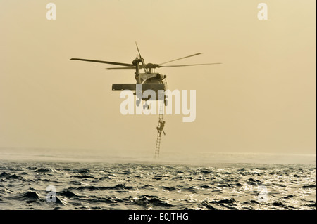 U.S. Air Force le personnel de sauveteurs-parachutistes de la 82e Escadron de sauvetage expéditionnaire, monter une échelle de corde à bord d'un SH-60 Sea Hawk Banque D'Images