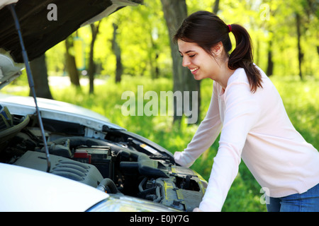 Happy woman ressemble sous le capot voiture contexte green park Banque D'Images