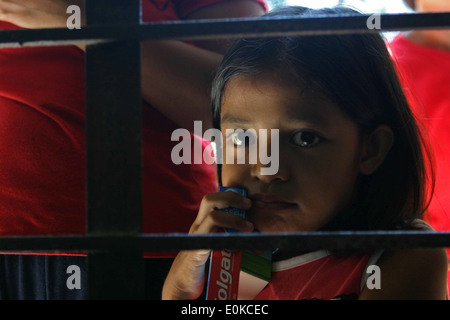 GUIMBA, Philippines-une fille Philippine regarde à travers une vitre avec son dentifrice après avoir reçu de l'aide dentaire forme servicemem Banque D'Images