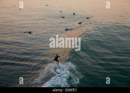 Une vue de derrière d'un surfeur attraper une vague que d'autres surfeurs de regarder en arrière plan à Steamers à Santa Cruz, en Californie. Banque D'Images