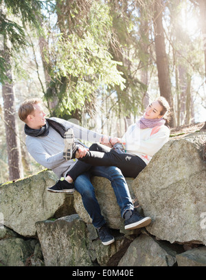 Jeune couple dans la nature repose sur de gros rochers dans les bois lors d'un trek. Relations sérieuses in ludique sur le bord d'un gros rocher. Banque D'Images