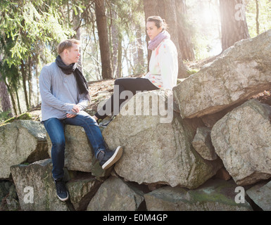 Jeune couple dans la nature repose sur de gros rochers dans les bois lors d'un trek. Banque D'Images