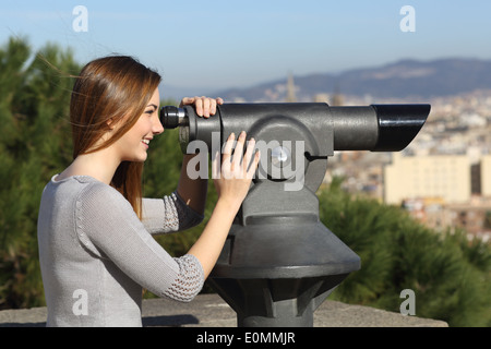 Femme regardant la ville touristique au moyen d'un télescope avec des bâtiments en arrière-plan Banque D'Images