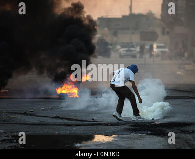 Ma'Ameer, Bahreïn. 16 mai, 2014. Un manifestant bahreïnite masqué tente de repousser une bombe de gaz lacrymogène lors d'une manifestation à Ma'ameer pour protester contre l'assassinat de l'activiste Ali Faisal Aekrawi (19 ans), qui a été tué le matin du vendredi 16 mai à l'hôpital. (Photo par Ayman Yaqoob/Pacific Press) Banque D'Images