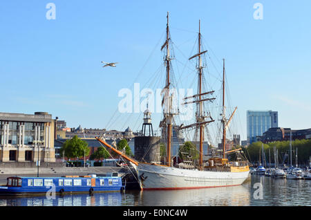 Bristol, Royaume-Uni. 17 mai, 2014. Un Cygne vole passé un grand voilier sur un emplacement calme et paisible matin comme le soleil se lève dans l'port flottant dans la ville de Bristol au Royaume-Uni. Les météorologues sont la prévision météo chaude et ensoleillée pour le week-end. Crédit : Robert Timoney/Alamy Live News Banque D'Images