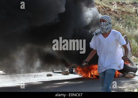 Ramallah, Palestine. 16 mai, 2014. Ramallah, Cisjordanie, territoire palestinien le 16 mai 2014 : manifestant palestinien lançant des pierres sur les soldats israéliens lors d'affrontements à l'extérieur de la prison d'Ofer israélienne-run, près de la ville de Ramallah, en Cisjordanie, le 16 mai 2014. un jour après que deux Palestiniens ont été tués par les forces israéliennes au cours d'affrontements à l'extérieur de la prison d'Ofer run-israélienne après une protestation à l'occasion de ''Nakba'' ou ''catastrophe'' de l'état juif de sa création. © Museitef NurPhoto Abdalkarim //ZUMAPRESS.com/Alamy Live News Banque D'Images
