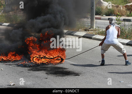 Ramallah, Palestine. 16 mai, 2014. Ramallah, Cisjordanie, territoire palestinien le 16 mai 2014 : manifestant palestinien se déplace en voiture en feu des affrontements à l'extérieur de l'tiresduring-israéliens exécuter la prison d'Ofer, près de la ville de Ramallah, en Cisjordanie, le 16 mai 2014. un jour après que deux Palestiniens ont été tués par les forces israéliennes au cours d'affrontements à l'extérieur de la prison d'Ofer run-israélienne après une protestation à l'occasion de ''Nakba'' ou ''catastrophe'' de l'état juif de sa création. © Museitef NurPhoto Abdalkarim //ZUMAPRESS.com/Alamy Live News Banque D'Images