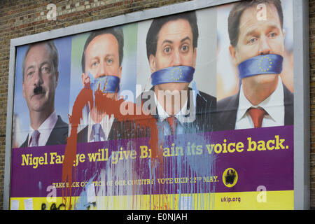 Londres, Royaume-Uni. 17 Mai 2014 : d'éclaboussures de peinture sur l'anti-adhésion à l'UE "UK Independence Party (UKIP) billboard politique qui montre leader Nigel Farage (avec moustache Hitler en torchis) et un bâillonné le premier ministre David Cameron, leader du parti travailliste Ed Milliband (coalition) et Vice-PM Nick Clegg - tous contre un silence de l'Union européenne, vu l'intimidation au 76200 - un quartier relativement aisé de le sud de Londres. L'annonce est affichée avant les élections européennes le 22 mai. Copyright Richard Baker / Alamy Live News. Banque D'Images