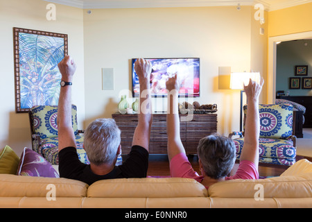 D'âge mûr en regardant un match de football sur la TV (Touchdown gestes telly) dans Showcase Accueil Résidentiel, USA Banque D'Images