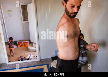 Le Camp de Zaatari, Al Mafraq, Jordanie. Feb 8, 2014. Les réfugiés de Zaatari EAAD - HARIRI, 39 ans, a été blessé à Deraa, en Syrie en novembre 2013 lors d'un bombardement. Malgré sa blessure, il est encore capable de s'occuper de sa jeune famille. Dans le désert jordanien, à 10 kilomètres de la frontière syrienne se trouve un camp de réfugiés de Zaatari appelé. C'est le foyer de plus de 110 000 personnes déplacées qui ont fui la guerre en Syrie depuis juillet 2012. La plupart de ces réfugiés sont originaires de la région sud de Deraa où les combats ont été parmi les pires vu dans la guerre civile en Syrie qui a traîné pendant plus de trois ans. T Banque D'Images