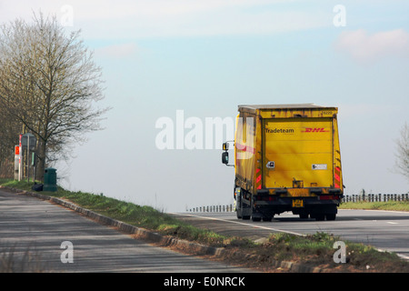 Un camion DHL en passant l'entrée d'une aire tout en voyageant le long de l'A417 à deux voies dans les Cotswolds, en Angleterre. Banque D'Images