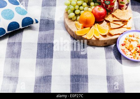 Réglage de pique-nique avec des fruits frais et des collations assis sur une couverture à carreaux pinic Banque D'Images